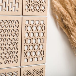 Può includere: Un set di sei pannelli da parete in legno con diversi motivi geometrici ritagliati. I pannelli sono disposti a griglia e sono realizzati in legno chiaro.