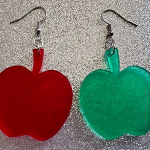 May include: A pair of dangle earrings featuring red and green apple shapes. The earrings are made of acrylic and have silver hooks.