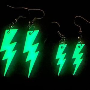 May include: Three pairs of glow-in-the-dark lightning bolt earrings. The earrings are made of green acrylic and have silver hooks.