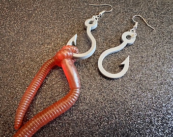 May include: A pair of gray fish hook earrings with a red worm dangling from one of the hooks.