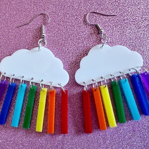 May include: White cloud shaped earrings with a rainbow of colored acrylic strips hanging from the bottom.