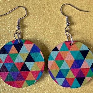 May include: A pair of colorful geometric pattern earrings with silver hooks. The earrings are round and feature a variety of colors, including pink, blue, green, yellow, and orange.