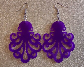 May include: A pair of purple octopus-shaped earrings. The earrings are made of a solid, opaque material and feature a detailed cut-out design of an octopus. The earrings hang from silver-colored fish hook ear wires.