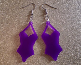May include: A pair of purple earrings shaped like a swimsuit. The earrings have silver hooks.