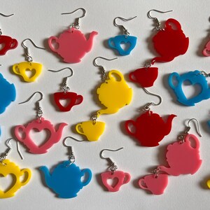 May include: Assortment of colorful acrylic earrings featuring teapots and teacups with heart cutouts. The earrings are available in pink, red, yellow, blue, and teal.