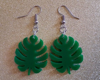 May include: A pair of green monstera leaf earrings with silver hooks.