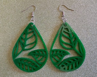 May include: A pair of green teardrop-shaped earrings with a leafy design. The earrings are made of a translucent material and have silver hooks.