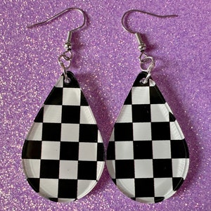 May include: A pair of checkerboard pattern teardrop shaped earrings with silver hooks.