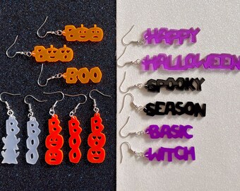 May include: A set of 10 Halloween-themed earrings. The earrings are made of acrylic and feature various Halloween-themed words and images, including "BOO", "HAPPY HALLOWEEN", "SPOOKY SEASON", and "BASIC WITCH".