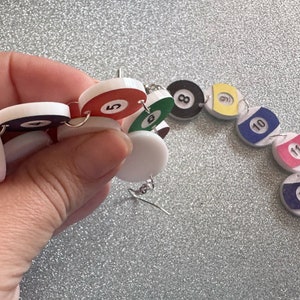 May include: A colorful necklace made of round, white, red, green, yellow, blue, and pink plastic beads with black numbers 5, 8, 10, 11, 12, and 13 printed on them.