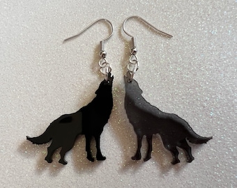 May include: A pair of black wolf silhouette earrings with silver hooks. The wolves are howling at the moon.