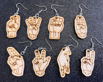 Può includere: Set di 10 orecchini in legno con diversi gesti delle mani. Gli orecchini sono realizzati in legno naturale e hanno ganci argentati.
