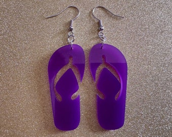 May include: A pair of purple flip-flop earrings with silver hooks. The flip-flops have a cut-out design in the shape of a horseshoe.