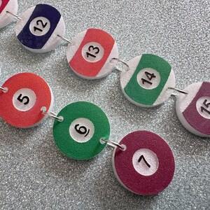May include: A chain of 10 round, white, foam-backed, felt circles with black numbers 1 through 15. Each circle has a different color: red, blue, red, green, red, green, maroon, maroon, green, maroon.