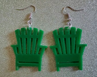 May include: A pair of green acrylic earrings shaped like Adirondack chairs. The earrings have silver hooks.