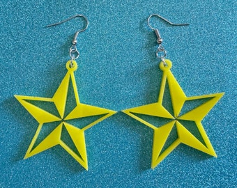May include: A pair of yellow star-shaped earrings with silver hooks. The stars have a five-pointed design with a smaller star in the center.