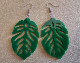 May include: A pair of green monstera leaf earrings with silver hooks. The leaves are cut out with a delicate design.