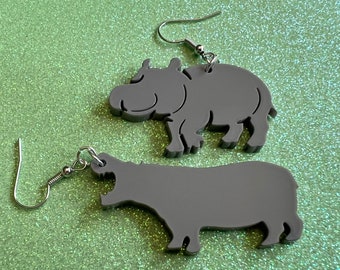 May include: A pair of gray hippopotamus earrings. The earrings are made of acrylic and have a simple, modern design. They are perfect for adding a touch of whimsy to any outfit.