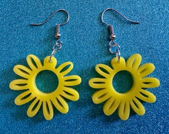 May include: A pair of yellow daisy-shaped earrings with silver hooks.