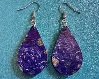 May include: A pair of silver teardrop-shaped earrings with a purple and white swirling pattern reminiscent of Van Gogh's Starry Night.
