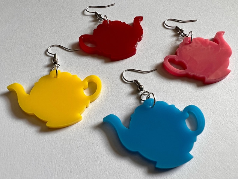 May include: Four pairs of teapot-shaped earrings. The earrings are made of acrylic and come in four colors: red, pink, yellow, and blue.