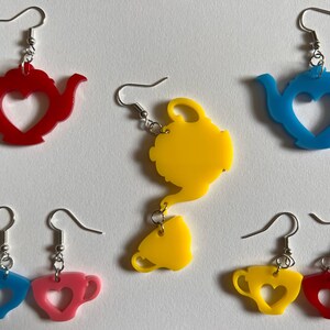 May include: A set of six colorful earrings featuring teapots and teacups with heart-shaped cutouts. The earrings are made of acrylic and come in red, blue, yellow, and pink.