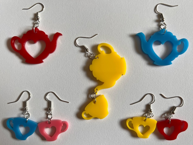 May include: A set of six colorful earrings featuring teapots and teacups with heart-shaped cutouts. The earrings are made of acrylic and come in red, blue, yellow, and pink.