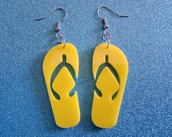 May include: A pair of yellow flip-flop earrings with silver hooks. The flip-flops are cut out and have a simple design.