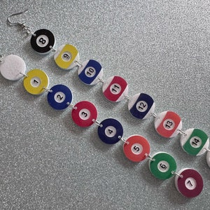 May include: A pair of earrings with a chain of 15 colorful round beads, each with a white number from 1 to 15, resembling billiard balls.