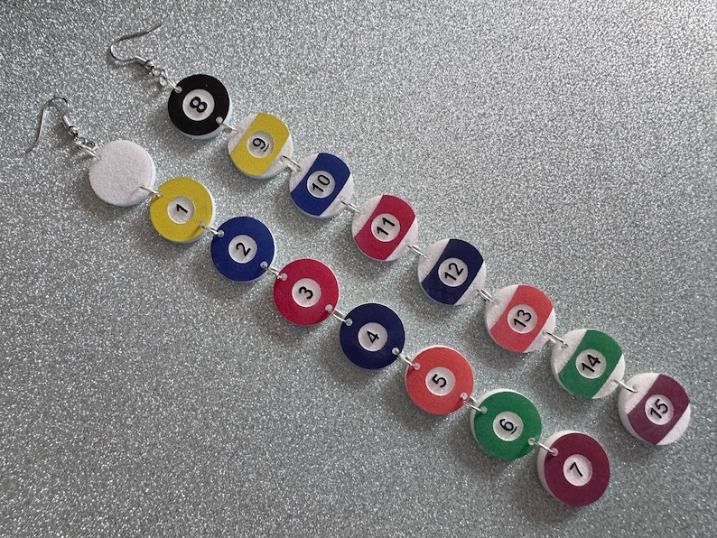 May include: A pair of earrings with a chain of 15 colorful round beads, each with a white number from 1 to 15, resembling billiard balls.