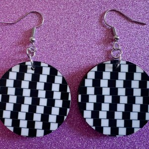May include: A pair of black and white checkered circle earrings with silver hooks.