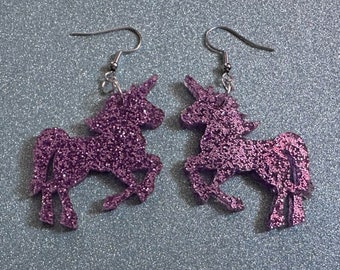 May include: A pair of purple glitter unicorn earrings with silver hooks.