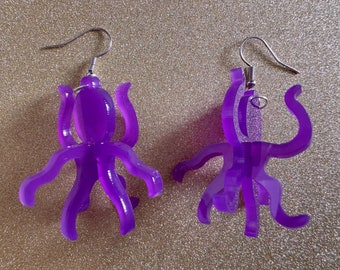 May include: A pair of purple octopus earrings. The earrings are made of acrylic and have a shiny finish. The octopus has eight tentacles and is hanging from a silver hook.