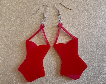 May include: A pair of red, acrylic earrings shaped like a one-piece swimsuit.