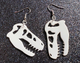 May include: A pair of white dinosaur skull earrings with silver hooks. The earrings are made of a lightweight material and are perfect for everyday wear.