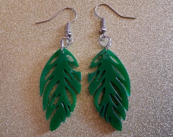 May include: A pair of green leaf-shaped earrings with silver hooks. The leaves have a cut-out design.