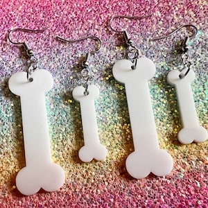 May include: Three pairs of white bone-shaped earrings with silver hooks. The earrings are different sizes.