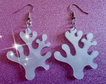 May include: A pair of frosted white acrylic earrings shaped like coral. The earrings have silver hooks.