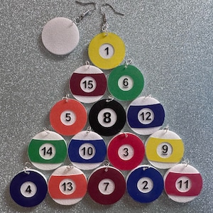 May include: A set of 15 earrings shaped like billiard balls, each with a different number from 1 to 15. The earrings are made of felt and have silver hooks.