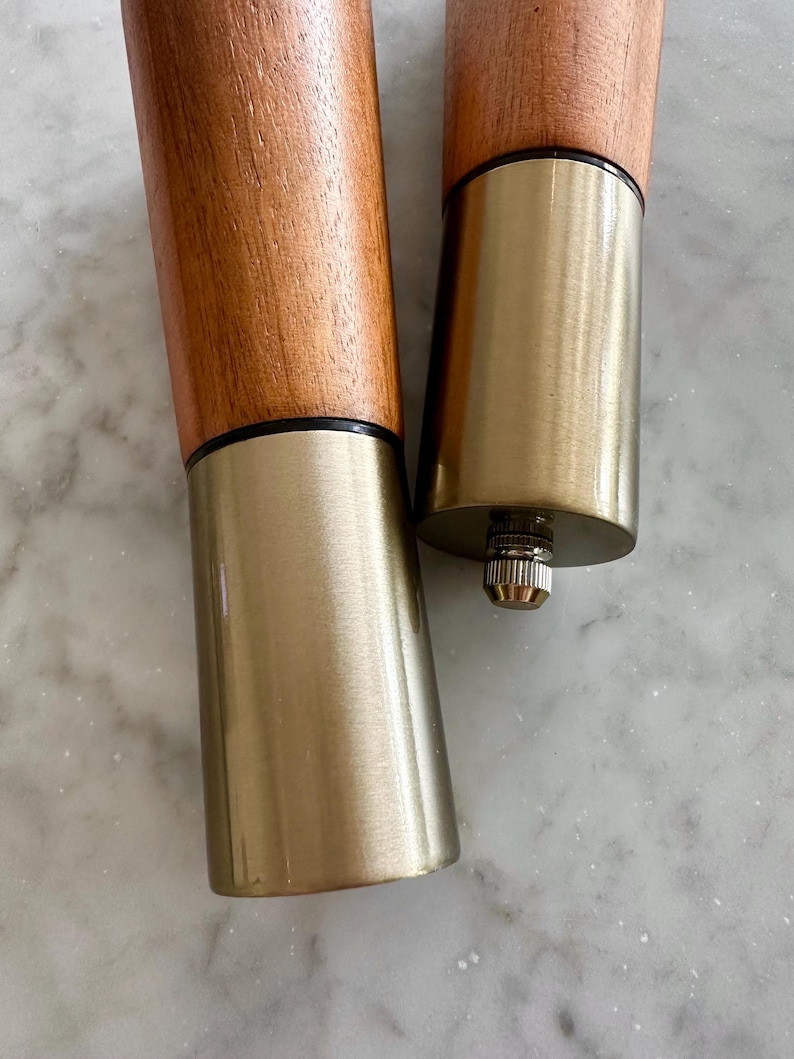May include: Two wooden furniture legs with a gold metal base. The legs are brown and have a dark brown band around the top of the wood.