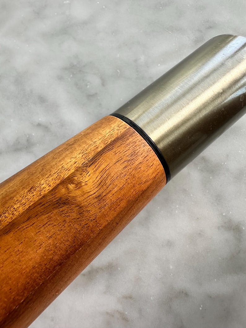 May include: A wooden rolling pin with a silver metal top. The wood has a natural brown color and a smooth finish.