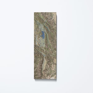 May include: A topographic map of a mountainous region with a large lake in the center. The map is printed on a textured surface and has a brown and green color scheme.