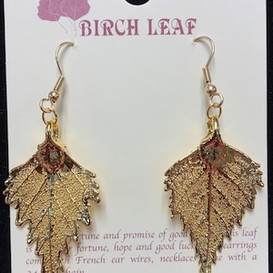Op de afbeelding: Gouden berkenblad oorbellen met een Franse draad sluiting. De kaart leest "Birch Leaf" en "tune and promise of good fortune, hope and good luck. Comes with French ear wires, necklaces and chain. C & J Sayles, Inc. 1-800-568-5341 MADE IN THE USA."