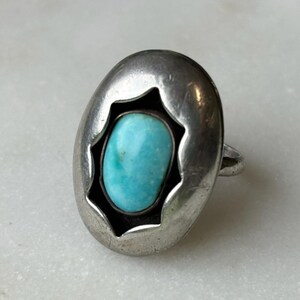 May include: A silver ring with a turquoise stone set in a starburst design.