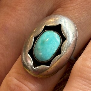 May include: A silver ring with a turquoise stone set in a starburst design.