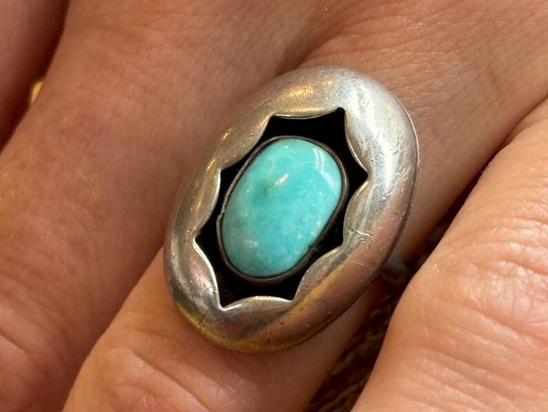 May include: A silver ring with a turquoise stone set in a starburst design.