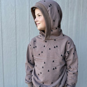 May include: A brown hooded sweatshirt with a black tree pattern. The sweatshirt has a double layer hood and a relaxed fit.