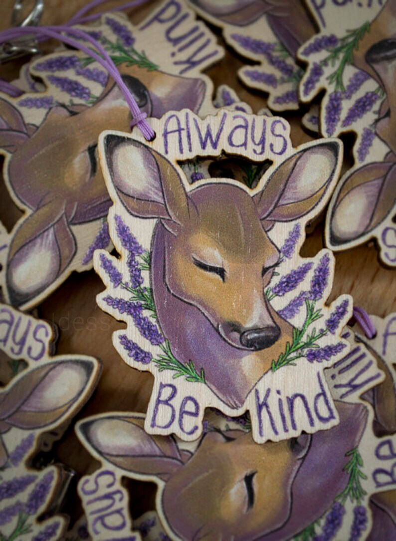 May include: Wooden keychain with a purple and brown deer illustration. The keychain has the text "Always Be Kind" around the deer.