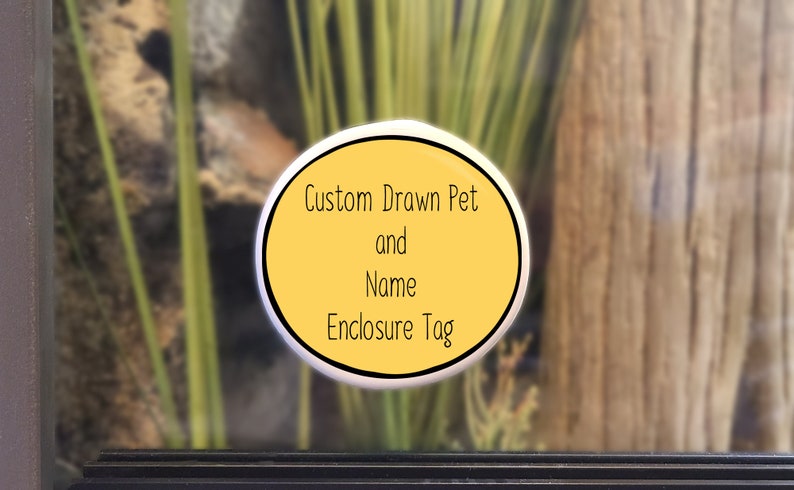 Op de afbeelding: Een gele ovale sticker met zwarte tekst die "Custom Drawn Pet and Name Enclosure Tag" luidt.