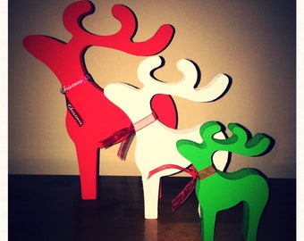 May include: Three wooden reindeer ornaments in red, white, and green. The reindeer are standing on a wooden surface. The red reindeer has the word "Christmas" written on it twice. The text "Little Gifts" is written on the bottom of the image.